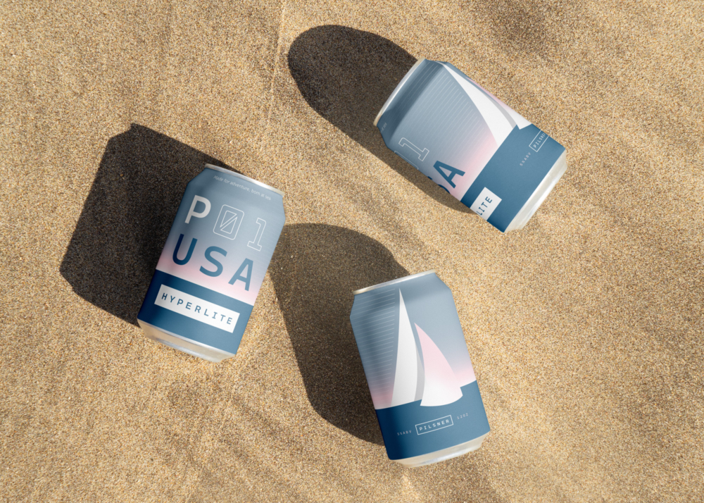 Three Hyperlite beer cans laying in the sand on the beach.