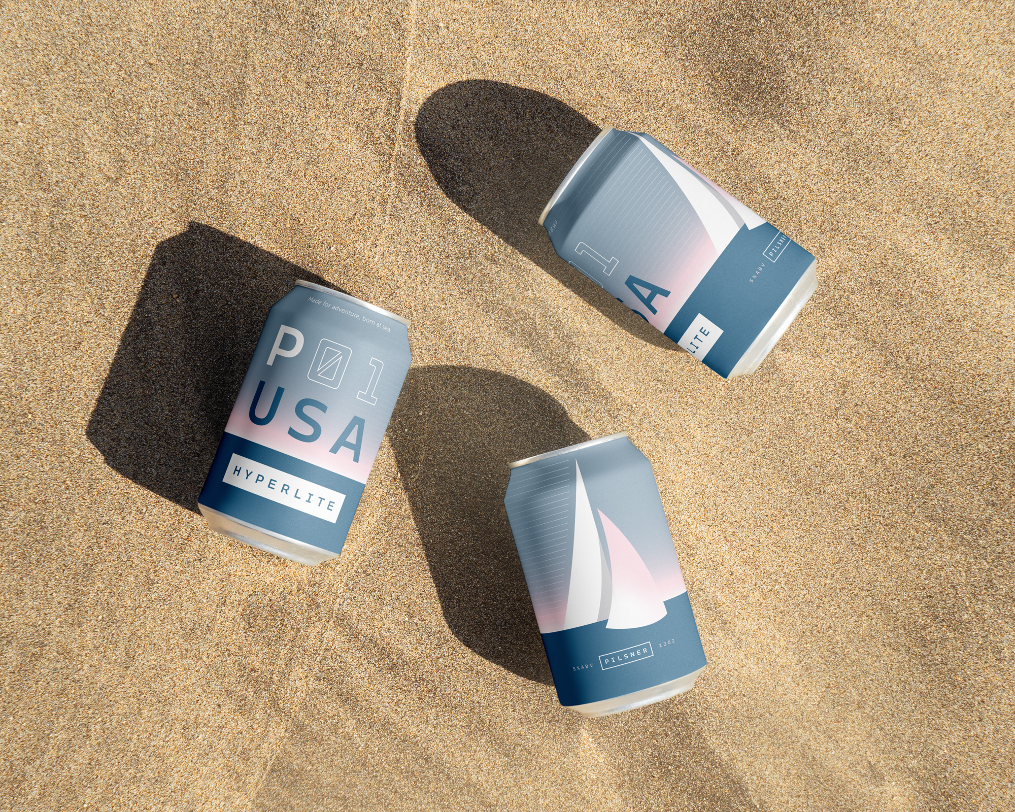 Three Hyperlite beer cans laying in the sand on the beach.