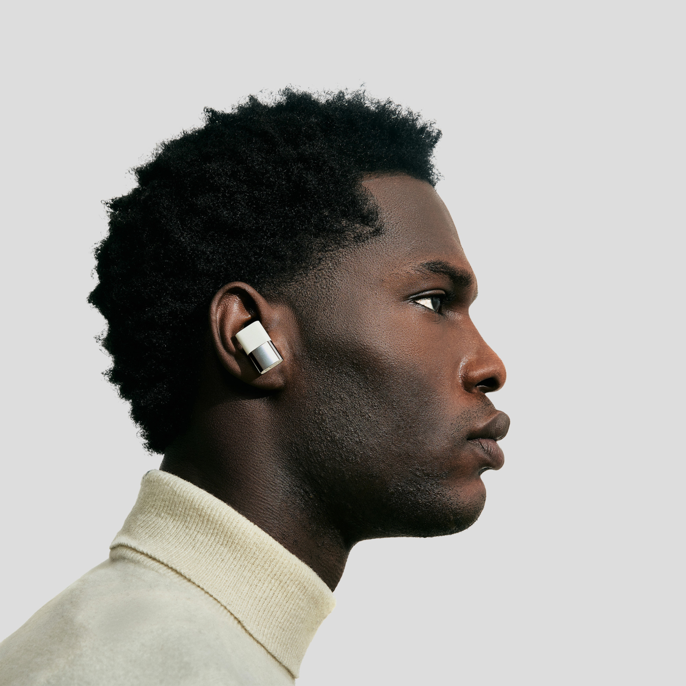 Model wearing the Status Between 3ANC earbuds in bone