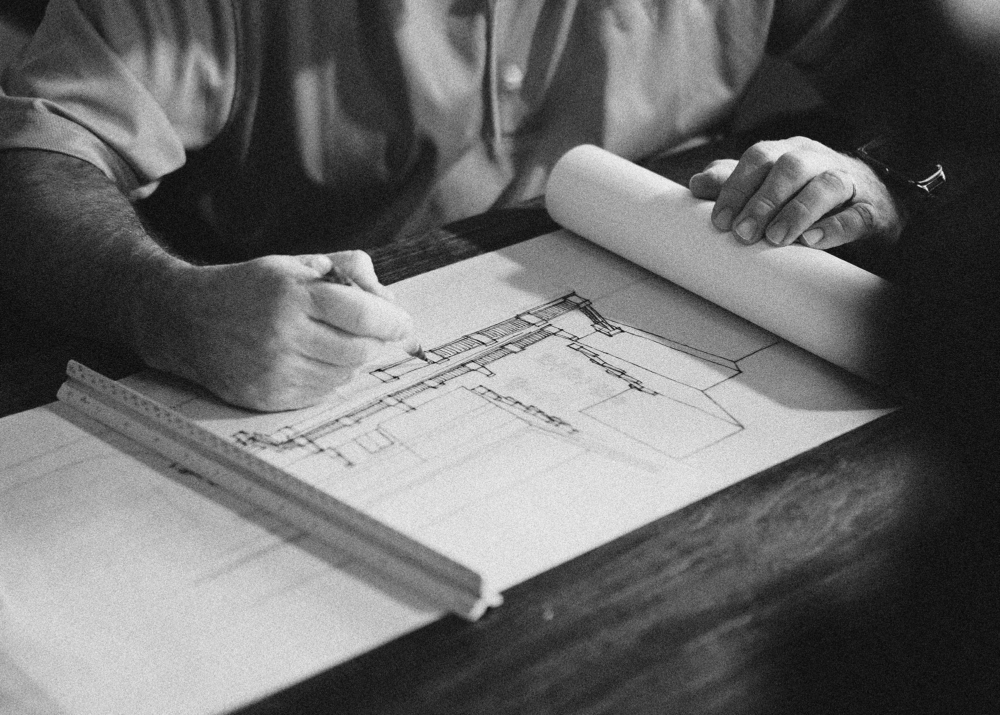 Black and white photograph of an architect working on building drawings