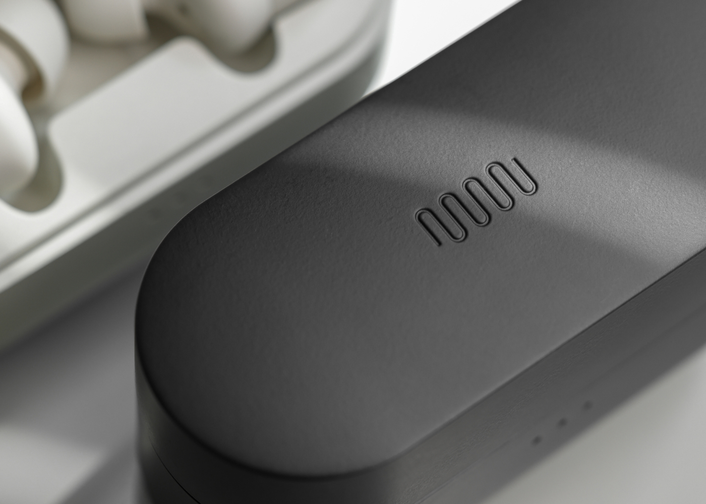 Photograph of the Status secondary brandmark engraved into the Between 3ANC earbuds charging case.